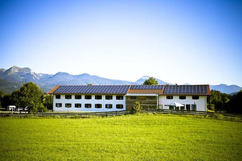 Foto der Jugendherberge in Mittenwald, deren Dach komplett mit einer Photovoltaik-Anlage ausgestattet ist